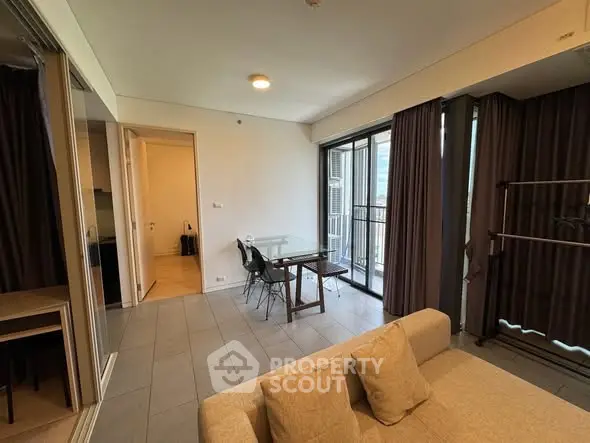 Modern living room with glass table and cozy sofa, featuring large windows and elegant curtains.