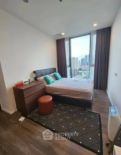 Modern bedroom with city view, featuring stylish decor and large windows for natural light.