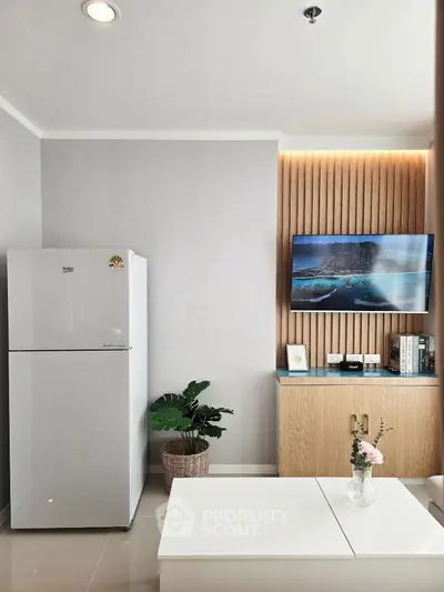 Modern living room with sleek fridge and mounted TV, elegant decor and bright ambiance.