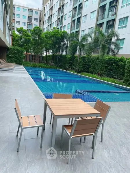 Modern apartment poolside with stylish outdoor furniture and lush greenery.