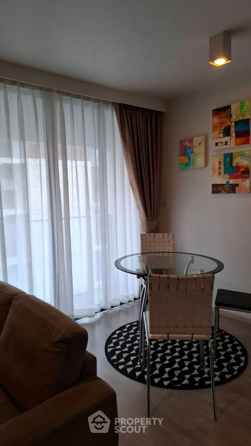 Chic modern living room with glass table and abstract art, perfect for urban living.