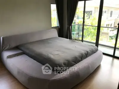 Spacious bedroom with modern bed and large windows offering natural light and garden view.