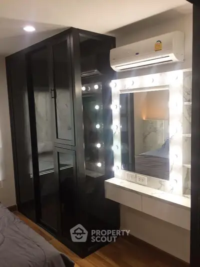 Stylish bedroom with illuminated vanity mirror and sleek black wardrobe, perfect for modern living.