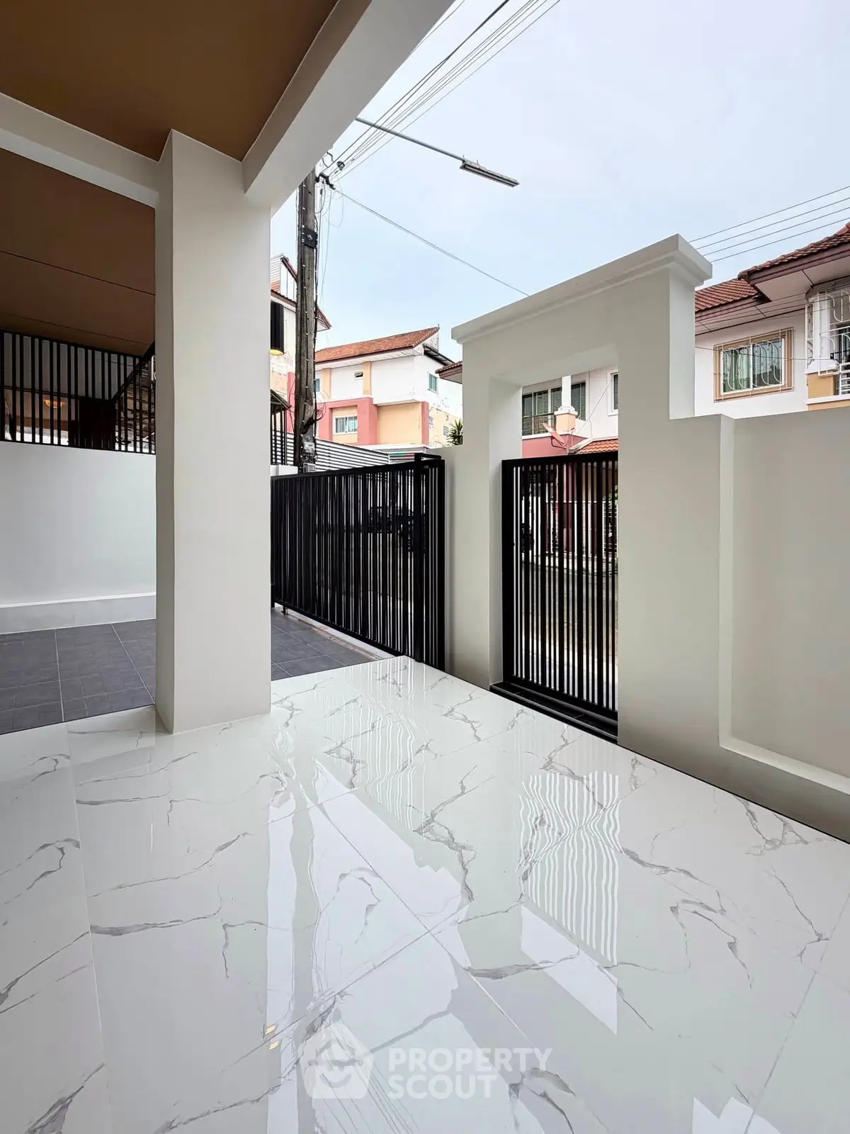 Modern home entrance with sleek marble flooring and stylish black gate.