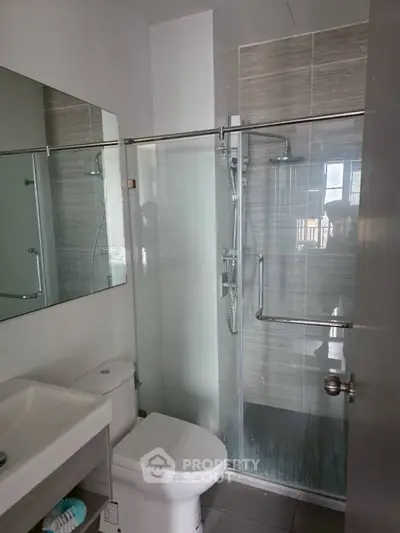 Modern bathroom with glass shower and sleek fixtures in a contemporary apartment.