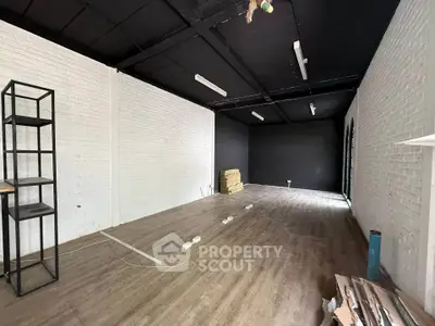 Spacious industrial-style room with white brick walls and wooden flooring, ideal for creative workspace.