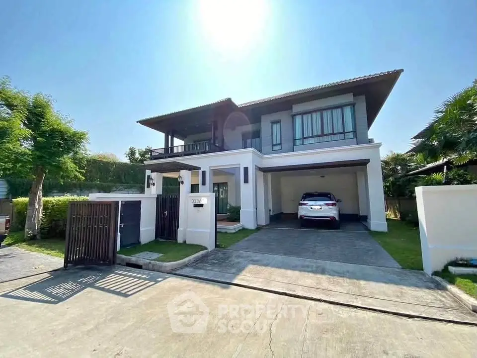 Modern two-story house with spacious driveway and lush greenery under clear blue sky.