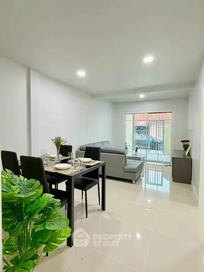 Modern living room with sleek dining area and cozy seating, featuring bright natural light and contemporary decor.