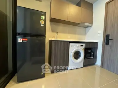 Modern kitchen with sleek appliances including fridge, washing machine, and microwave in compact layout.