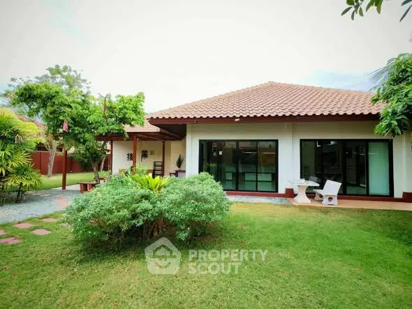 Charming single-story home with lush garden and patio seating, perfect for outdoor relaxation.