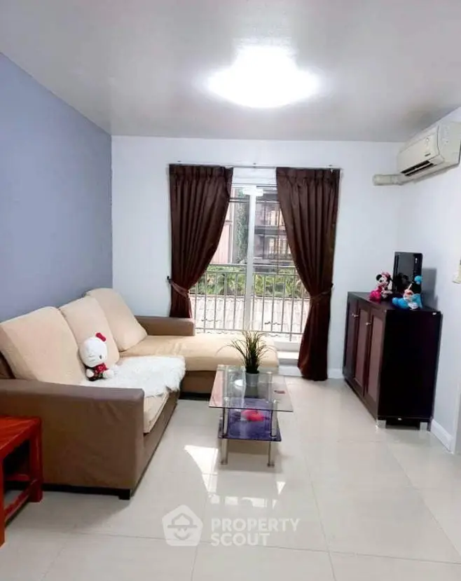 Cozy living room with modern decor, featuring a comfortable sofa, air conditioning, and a large window with curtains.
