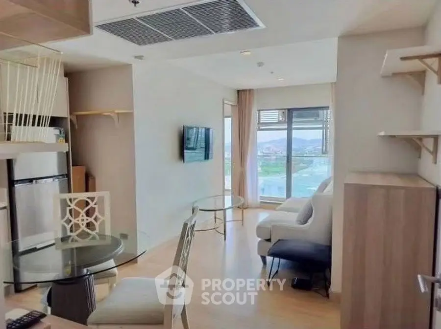 Modern living room with large window offering scenic view, stylish furniture, and open layout.