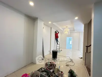 Spacious interior under renovation with modern lighting and white walls, showcasing potential for customization.