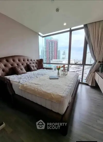 Luxurious bedroom with panoramic city view and elegant furnishings in a high-rise apartment.
