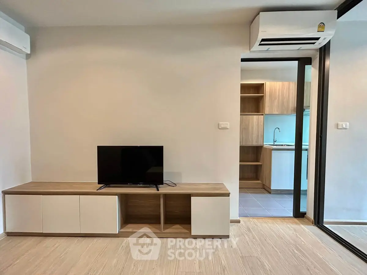 Modern living room with sleek TV stand and view into stylish kitchen