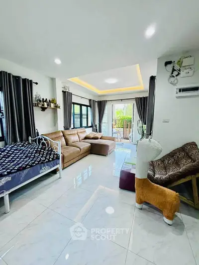 Spacious living room with modern decor and large windows opening to a balcony.