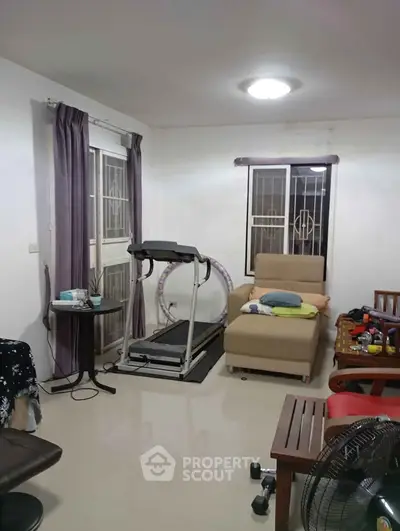 Cozy living room with treadmill and modern furniture, perfect for relaxation and exercise.