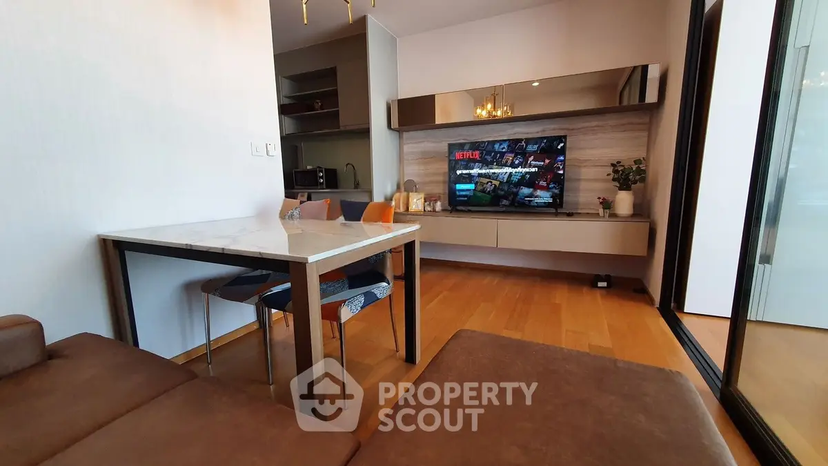 Modern living room with sleek furniture and wall-mounted TV, featuring a cozy dining area and stylish decor.