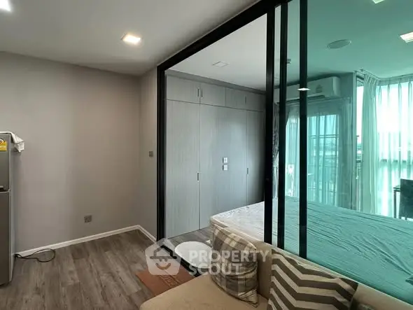Modern apartment interior with glass partition, cozy living area, and natural light.