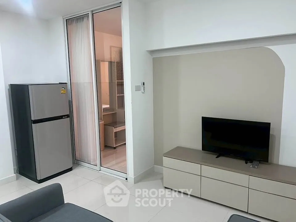 Modern living room with sleek furniture and sliding glass door to adjacent room.