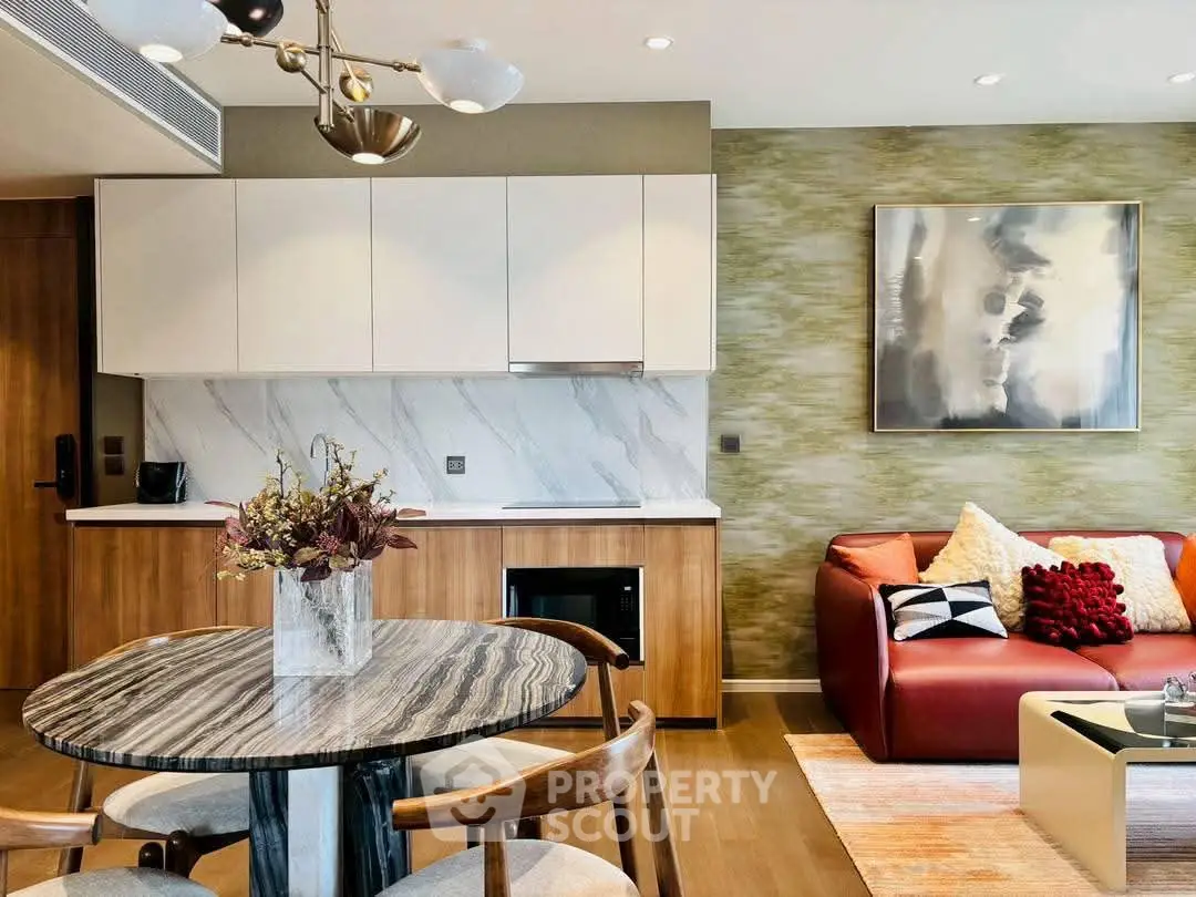 Modern living room with stylish kitchen and elegant decor, featuring a cozy seating area and contemporary artwork.