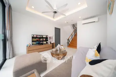 Modern living room with stylish decor, ceiling fan, and staircase in a bright, airy space.