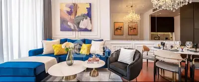 Luxurious living room with elegant decor, blue sofa, modern art, and chandelier lighting.