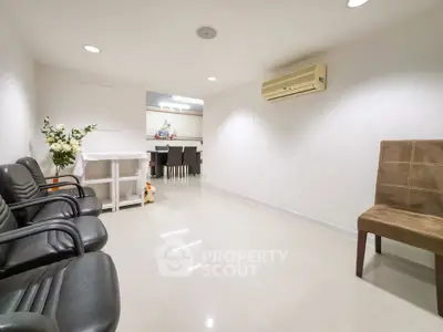 Spacious living area with modern seating and air conditioning, leading to a dining space.