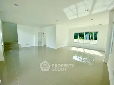 Spacious sunlit living room with glossy tiled floors and large windows