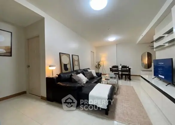 Spacious modern living room with sleek black sofa and elegant dining area, perfect for entertaining.