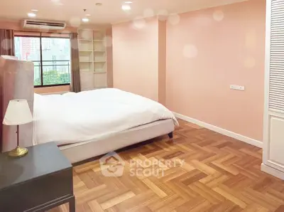 Spacious bedroom with parquet flooring and large window offering city views.