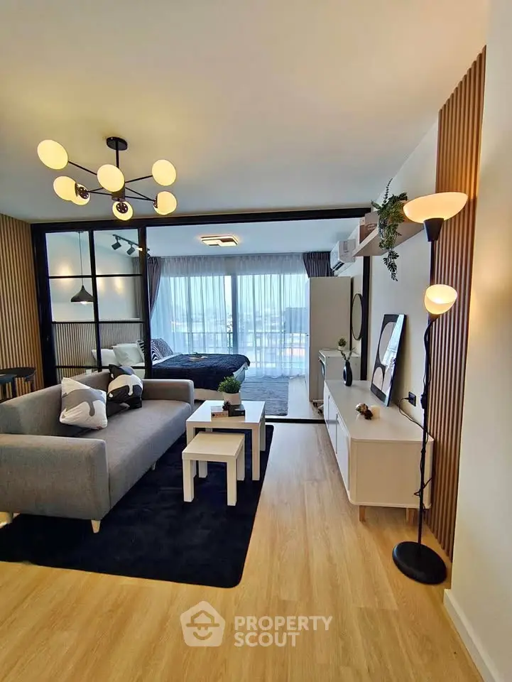 Modern living room with stylish decor and open layout leading to a cozy bedroom area.