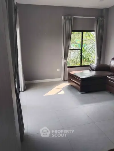 Spacious living room with modern decor and large window offering natural light.