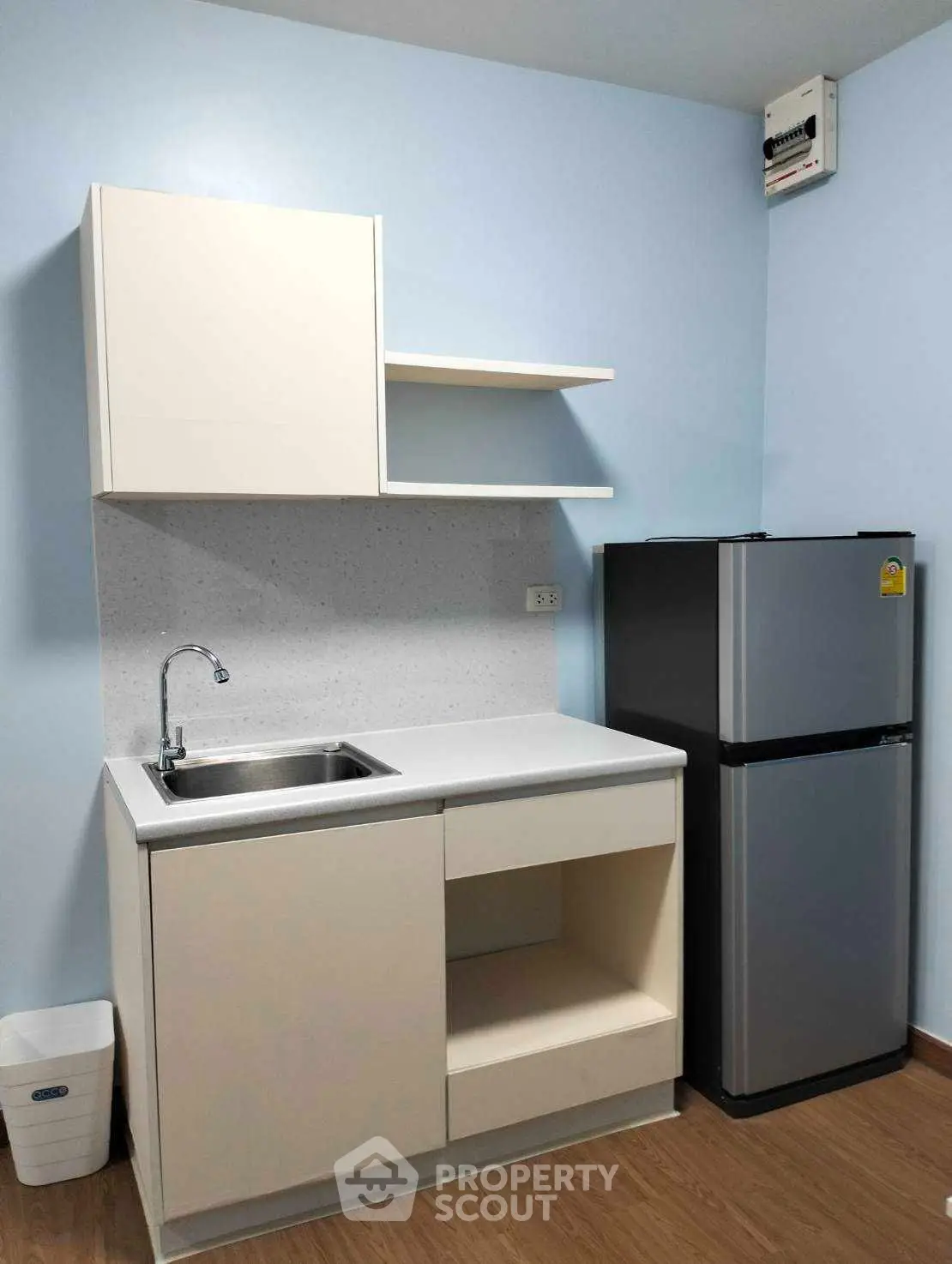 Compact kitchen with modern cabinetry and sleek refrigerator in cozy apartment.