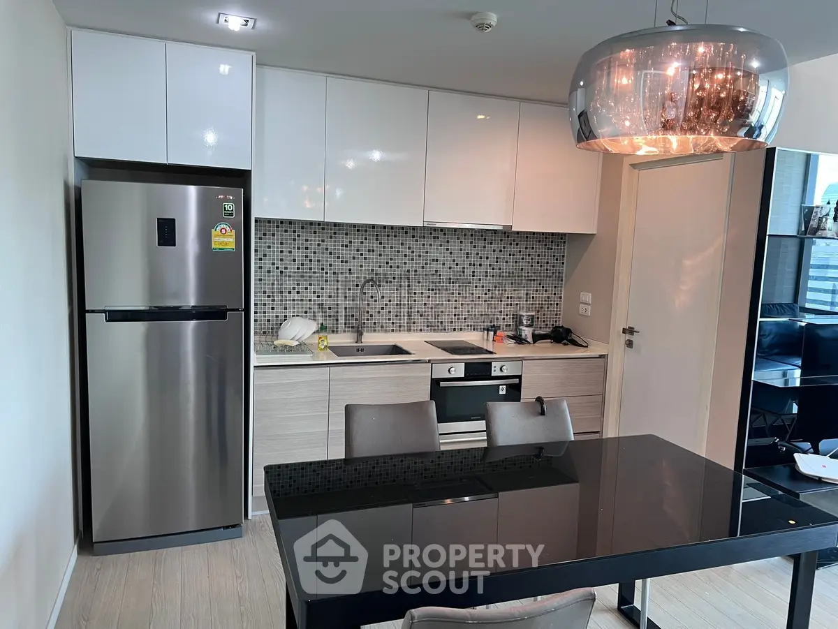 Modern kitchen with sleek appliances and stylish dining area in a contemporary apartment.
