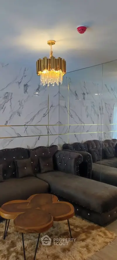 Luxurious living room with elegant chandelier and plush sofa, featuring marble accent wall and stylish coffee table.