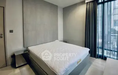 Modern bedroom with large window and minimalist design in urban apartment.