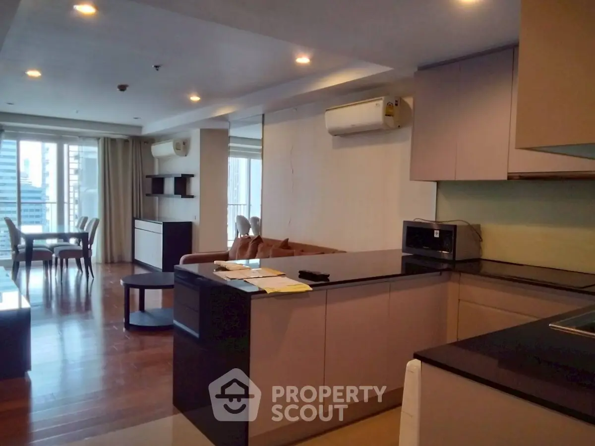 Spacious open-plan living room with modern kitchen and dining area, featuring city views.