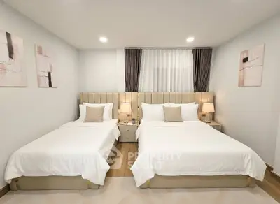 Elegant bedroom with twin beds, modern decor, and soft lighting for a cozy ambiance.