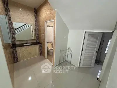 Spacious bathroom with modern fixtures and sleek tile design, featuring a large mirror and ample storage space.