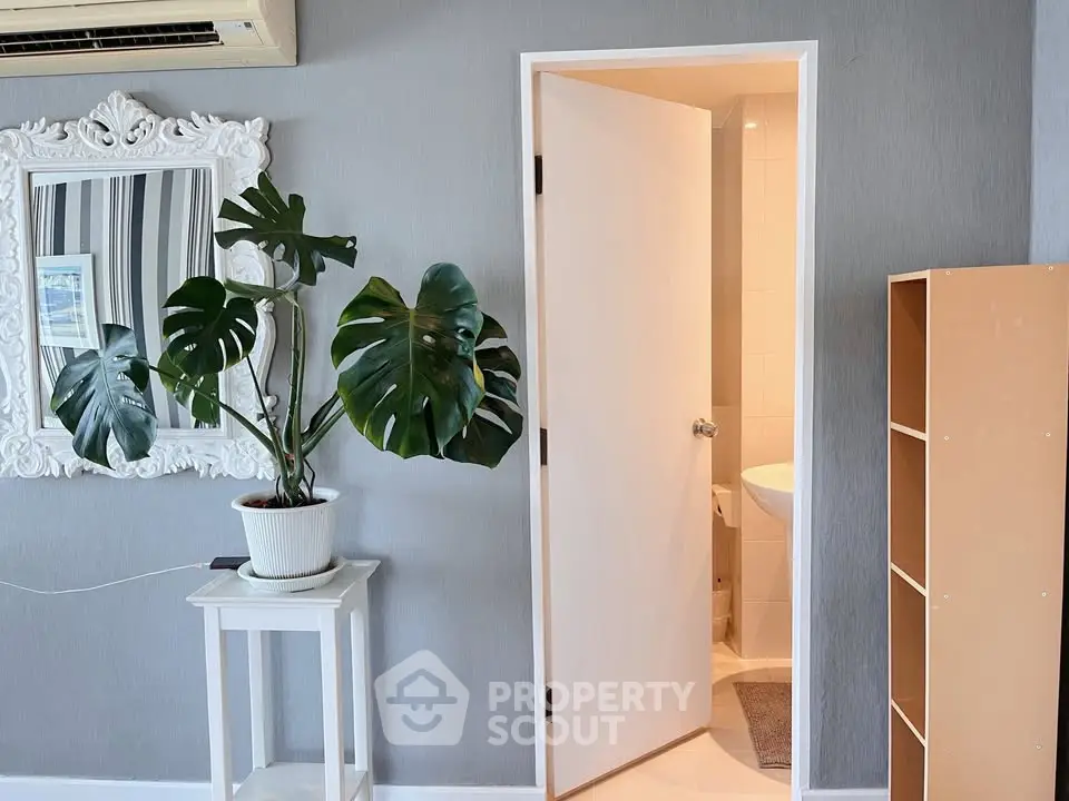 Charming interior with elegant decor and lush plant, featuring a glimpse into a modern bathroom.