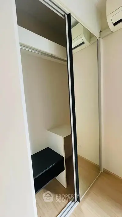 Spacious walk-in closet with sliding mirror doors and modern design.