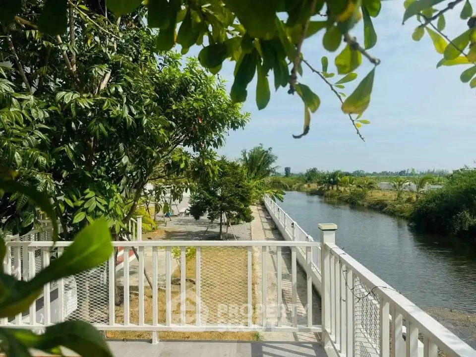 Charming riverside view from a spacious balcony with lush greenery and serene waterway.