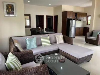 Spacious living room with modern wicker furniture and open kitchen layout.
