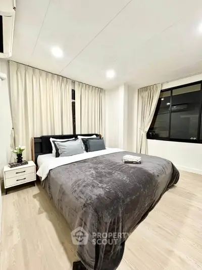 Modern bedroom with cozy bedding and elegant curtains in a stylish apartment.