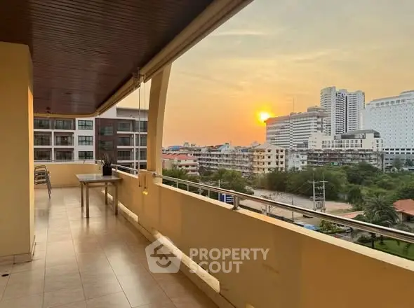 Spacious balcony with stunning city view at sunset, perfect for relaxation.