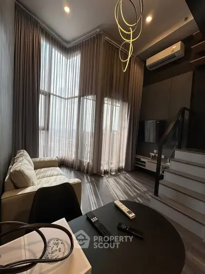 Modern living room with high ceilings, large windows, and stylish lighting in a contemporary apartment.