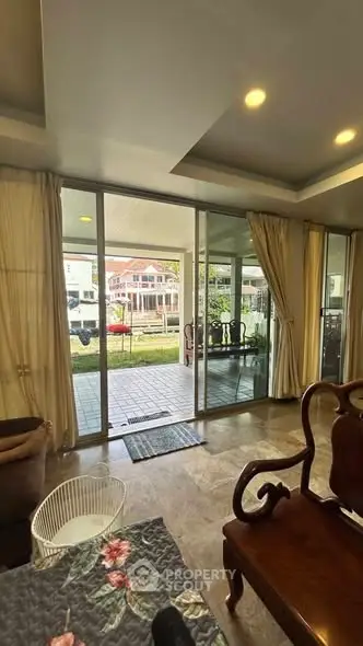 Spacious living room with large glass doors opening to a charming patio and garden view.