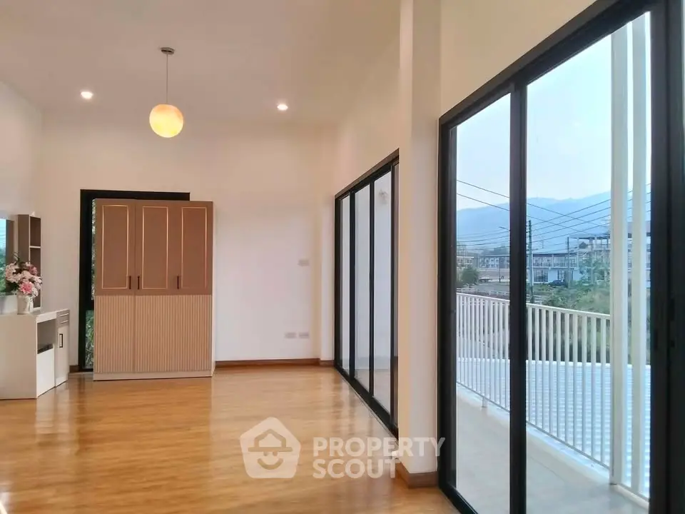 Spacious modern living room with large glass doors opening to a balcony with scenic views.