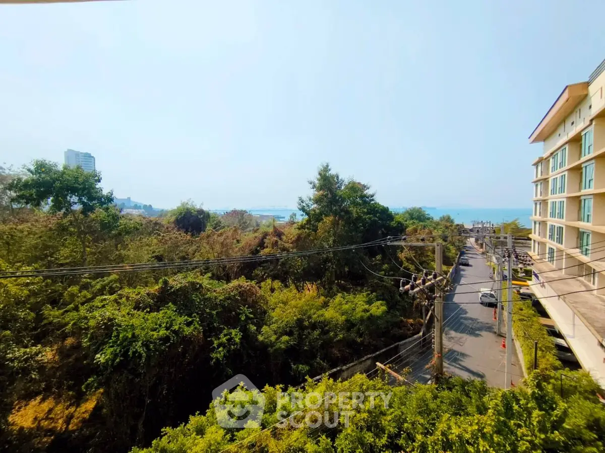 Stunning coastal view from a modern building balcony, showcasing lush greenery and serene ocean vistas.